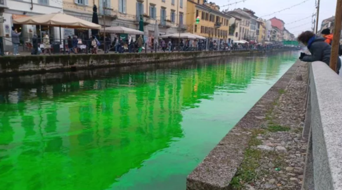 Blitz di Extinction Rebellion sui Navigli a Milano, liquido verde tinge l’acqua: “Il governo parla, la terra affonda”